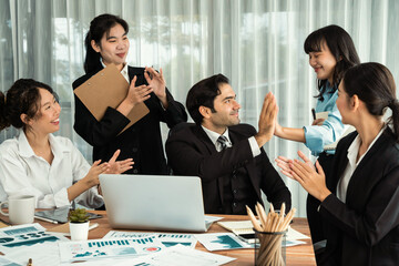 Group of happy businesspeople in high five gesture and successful efficient teamwork. Diverse race office worker celebrate after made progress on marketing planning in corporate office. Habiliment