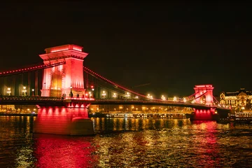 Szechenyi chain bridge with red lighting, at night, in Christmas Budapest