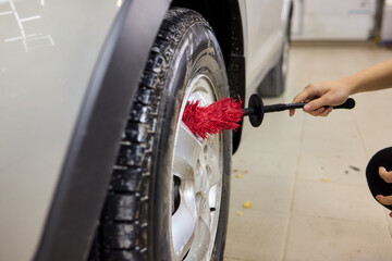 Cleaning car wheel thoroughly with brush and soap for maintenance and shiny result