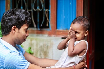 South asian hindu religious child learning the cultural gestures of showing respect from his father 