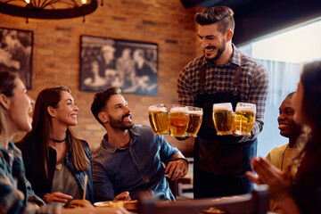 Happy waiter serving beer to group of guests in pub.