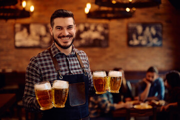Portrait of happy waiter serving beer and looking at camera.