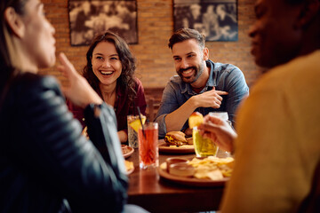 Happy couple talking to their friends while eating in pub.