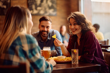 Happy woman talking to her friends in pub.