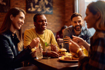 Group of happy friends enjoying in drinks and conversation in bar.