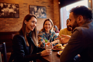 Happy woman talking to her friends while gathering with them in pub.