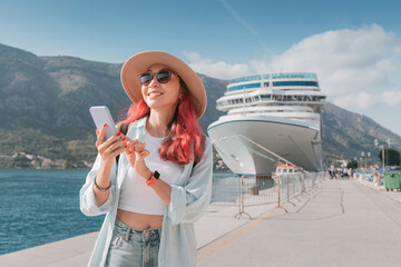Young woman using smartphone while enjoying vacation near cruise ship in Kotor, Montenegro © EdNurg
