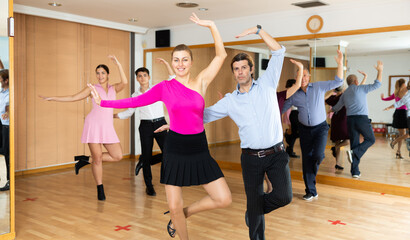 Fototapeta premium Happy woman and man enjoying active rock and roll dance in modern studio. Adult hobbies concept