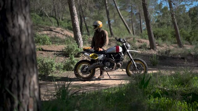 Hombre aventurero en moto de campo por el bosque de dia tomando fotos y videos