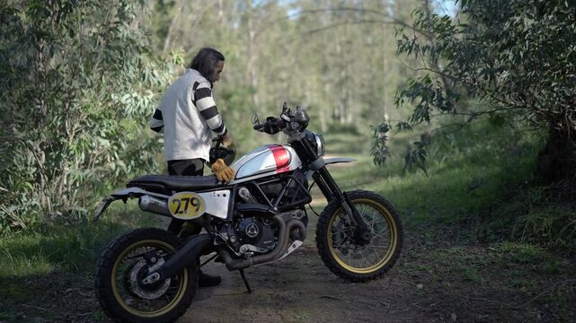Hombre aventurero en moto de campo por el bosque de dia tomando fotos y videos