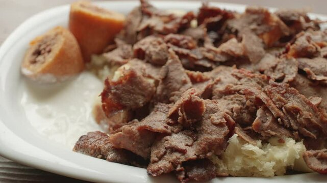 Local Turkish dish Iskender doner on an oval plate in slow motion