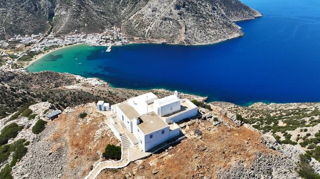 Aerial drone cinematic video with stunning view from uphill chapel of Prophet Elias of Troulaki overlooking port of Kamares, Sifnos island, Cyclades, Greece