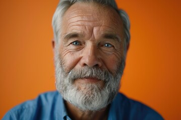 Obraz premium Elderly man in blue shirt smiling on orange background