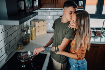 Lesbian couple cooking together and showing affection in modern kitchen