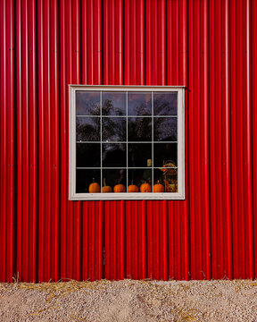 red barn with pumpkins in the window sill, symmetrical.