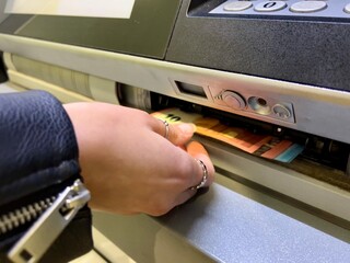 hand withdrawing cash from atm
