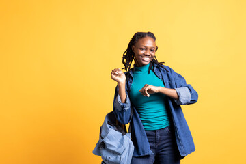 Student with backpack having fun, dancing on rhythm, enjoying free time. Joyous young girl relaxing...