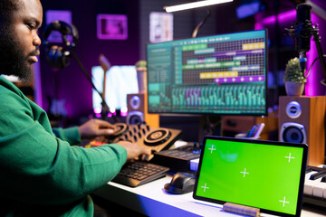 Fototapeta premium Producer composer mixing and mastering his songs with stereo tools, copyspace screen on a tablet. Audio technician improving sound quality on tracks recorded in post production.