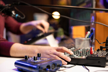 Sound engineer twisting pre amp knobs to mix and master songs on stereo equipment, working with...