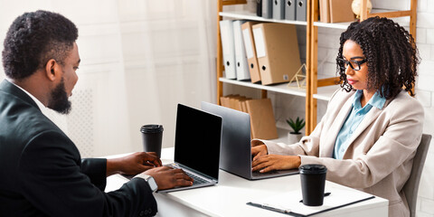Obraz premium Black millennial woman and her colleague working together in open space office. Panorama