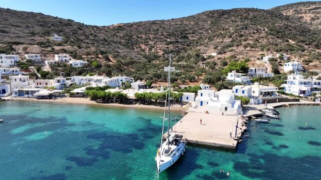 Aerial drone cinematic video of picturesque seaside fishing village of Vathy featuring landmark chapel of Taxiarchis, Sifnos island, Cyclades, Greece
