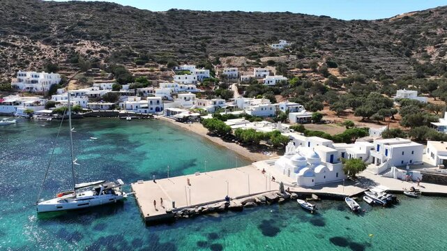 Aerial drone cinematic video of picturesque seaside fishing village of Vathy featuring landmark chapel of Taxiarchis, Sifnos island, Cyclades, Greece
