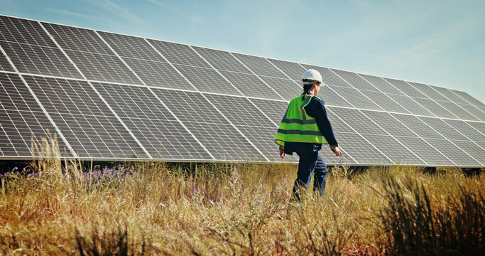 Solar panels, walk and grid with woman in nature for photovoltaic technician, renewable energy or power generator. Sustainability, electric system or inspection with engineer in outdoor for project