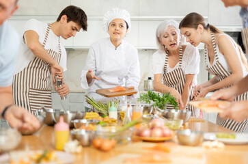 Professional personal chef cook in customer private kitchen house giving a cooking lesson to people...