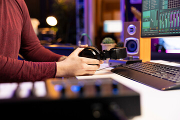 Artist preparing electronic gear for audio recording session in his home studio, using headphones...