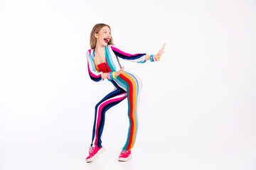 Young woman in vibrant striped outfit striking a playful pose against a white background, capturing trendy retro vibes