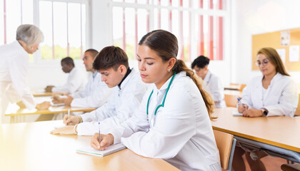 Focused young girl medical intern listening to lecture at university for professional development...
