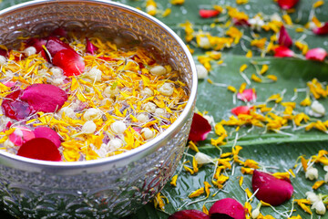 Water with jasmine flower, marigold petals and rose petals in silver bowl. Thai tradition, Songkran festival concept