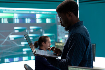 Governmental hackers breaching network security with advanced techniques, cyber defense in action. Team of IT experts working on gaining access to collect information, big screen.