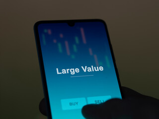 An investor analyzing the large value etf fund on a screen. A phone shows the prices of Large Value