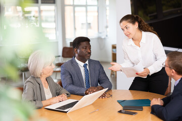 Business men and woman engaged in conversation sitting around table in conference room