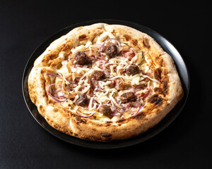 pizza with onions, bacon and chestnuts, on black background