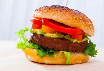 Delicious vegetarian hamburger with soybean patty and fresh vegetables at plate