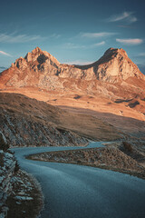 Scenic view of a winding road leading towards stunning mountain peaks bathed in the warm glow of sunset in Durmitor national park, Montenegro