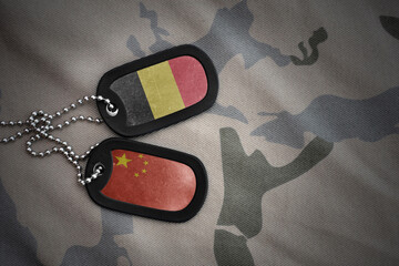 vintage army blank, dog tag with flag of belgium and china on the khaki texture background....