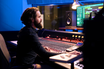 Audio engineer operating pc software for mixing and mastering tracks in studio, editing songs on...