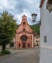The red Holy Spirit Hospital Church in Fussen, Germany, is located by the Lech River.