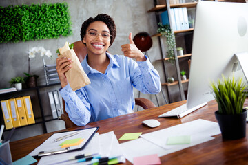 Confident businesswoman in a formal blouse enjoying a healthy snack break in her office while...