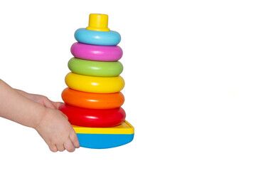 Toy pyramid in hands of child isolated on white background. Early development. Copy space.