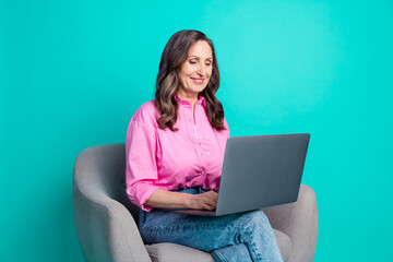 Photo of shiny attractive lady dressed pink shirt sitting chair working modern gadget empty space isolated teal color background