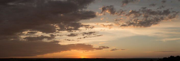 Landscape at sunset. Tragic gloomy sky. Panorama. Crimson twilight. Heavy, gloomy, dark clouds.