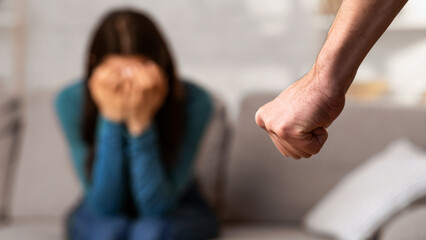 Domestic Violence During Quarantine. Man threatening his girlfriend with fist, scared woman hiding...