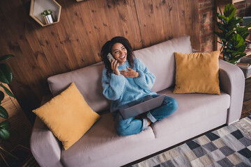 Obraz premium Charming young woman enjoying a phone call in a cozy living room setting on a relaxing autumn day