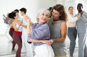 Adult couples of dancers, engaged in a dance studio, studying salsa in lesson