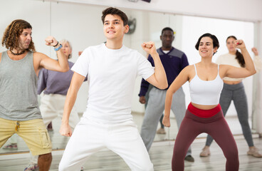 Caucasian man rehearsing modern dance with group in dance school