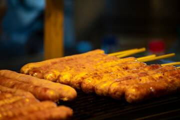 Golden brown sausages are neatly lined up on the grill